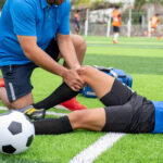 Footballer wearing a blue shirt, black pants injured in the lawn during the race.