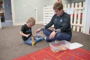 A Physical Therapist at Kinetic Edge Physical Therapy Center works with an infant on crossing midline tasks to help progress to crawling