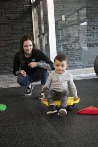 A Physical Therapist at Kinetic Edge Physical Therapy Center works with an infant on crossing midline tasks to help progress to crawling